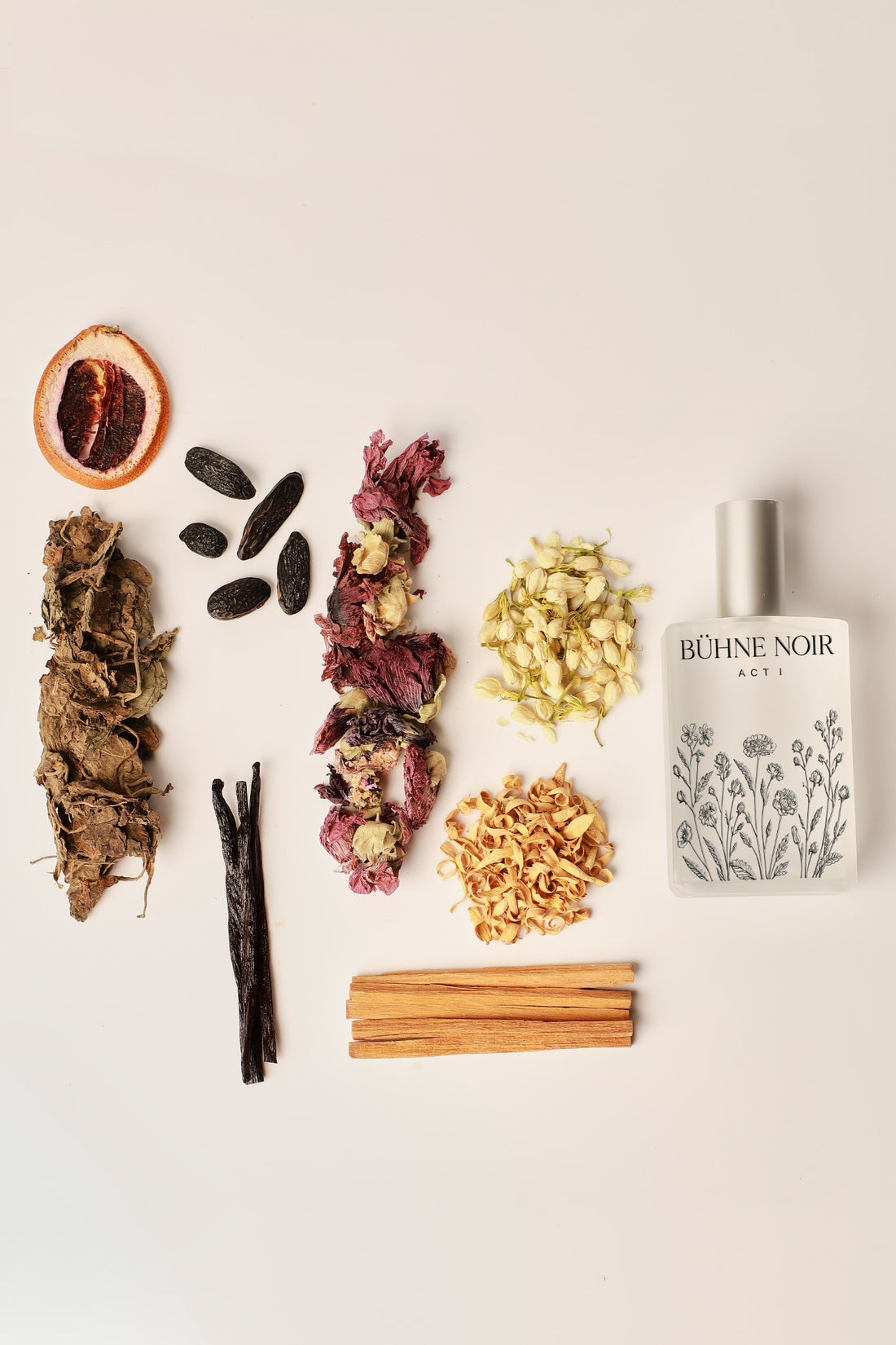 BÜHNE NOIR ACT I fragrance bottle arranged beside botanicals and aromatic ingredients.